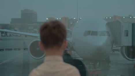 Junge-Schaut-Durch-Das-Flughafenfenster-Auf-Das-Flugzeug