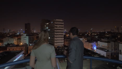 Couple-on-rooftop-looking-at-night-Tel-Aviv-and-having-drinks-Israel