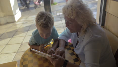 Child-and-grandma-using-tablet-PC-in-cafe