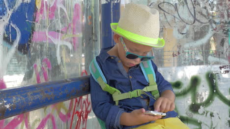 Boy-with-smartphone-at-grungy-city-bus-stop