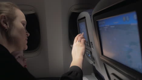 Mom-teaching-son-to-use-seat-monitor-in-plane