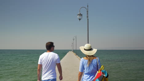 Couple-win-rolling-bag-walking-on-the-pier