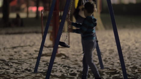 Child-having-fun-with-empty-swings-on-playground-in-the-evening