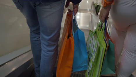 Couple-with-shopping-bags-riding-escalator