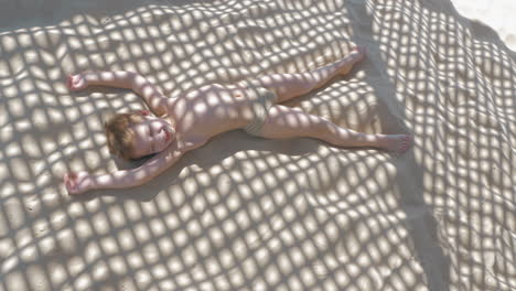 Child-making-sand-angel-when-relaxing-on-the-beach