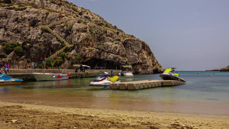 Zeitrafferaufnahmen-Zeigen-Boote-Und-Jetskis,-Die-Am-Strand-Von-Xlendi-Auf-Malta-Anlegen