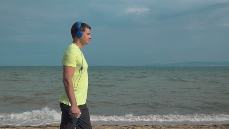 Man-Jogging-on-the-Beach-with-Smartphone