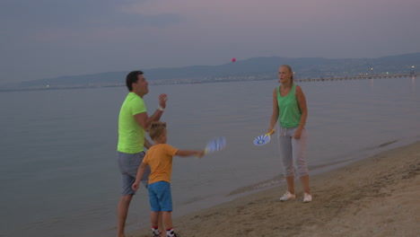Kind-Und-Eltern-Spielen-Tennis-Am-Strand