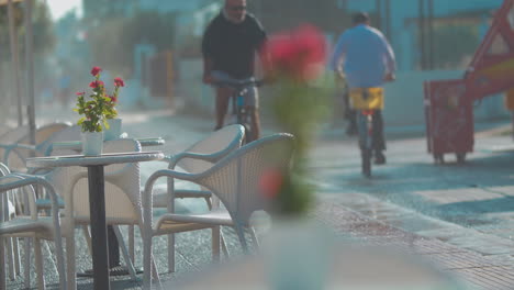 Cyclists-passing-by-empty-street-cafe