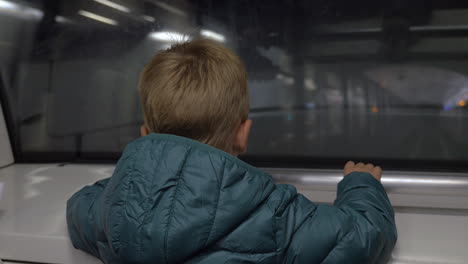 Child-looking-at-railway-from-moving-subway-train