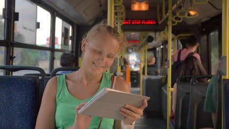Lächelnde-Frau-Tippt-Im-Bus-Ein-Tablet-Ein