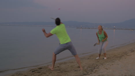 Young-couple-entertaining-themselves-with-tennis-on-the-beach