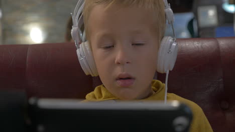Kid-in-headphones-watching-cartoon-on-smart-phone