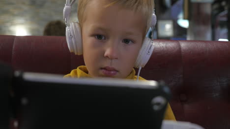 Child-in-headphones-watching-cartoon-on-mobile