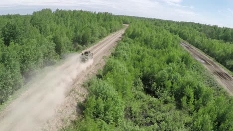 Flying-over-military-vehicle-on-dirt-road-in-woodland