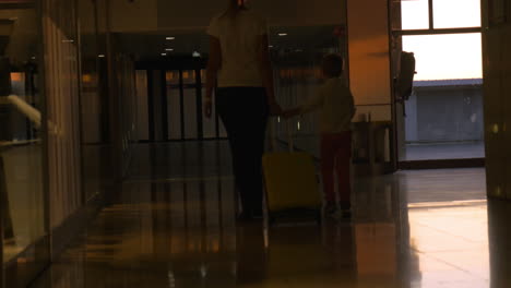 Mother-and-child-rolling-suitcase-at-the-airport