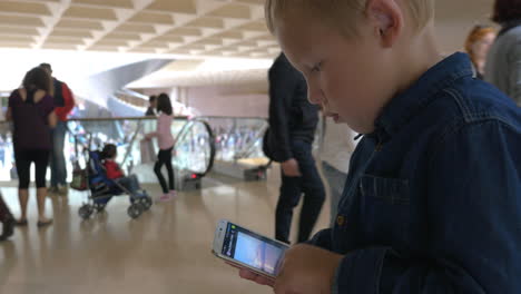 Kid-using-smart-phone-in-busy-shopping-centre