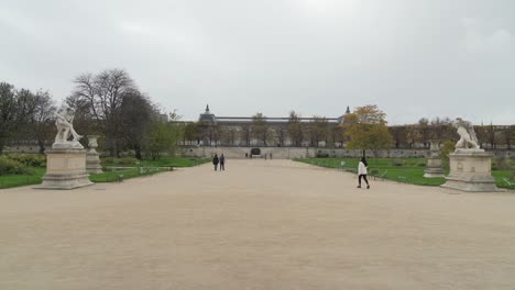 Parisians-Pass-Place-du-Carrousel-garden-on-Rainy-Day-in-Paris