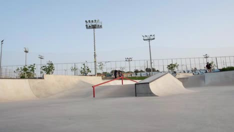 Young-skateboarder-performing-tricks-at-skatepark,-rail-trick-skateboarder