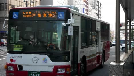 Local-busses-driving-on-the-city-streets-of-Hiroshima,-urban-city-static-shot