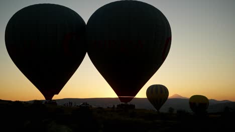 Silhouettierte-Heißluftballons-Starten-Am-Frühen-Morgen-Bei-Sonnenaufgang