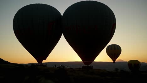 Silhouetted-hot-air-balloons-take-off-early-morning-sunrise-flight
