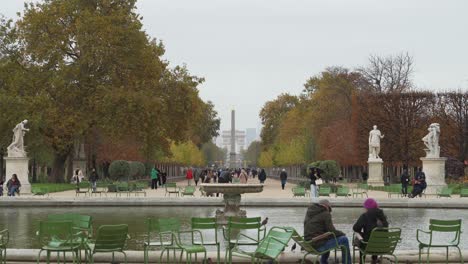 Fountain-and-Parisians-Walking-in-Place-du-Carrousel-garden-with-Arc-de-Triomphe-in-Distance