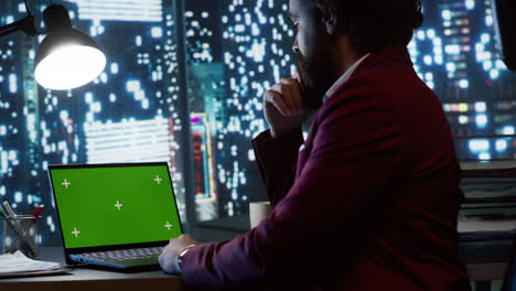 Company-CEO-works-with-laptop-and-greenscreen-display