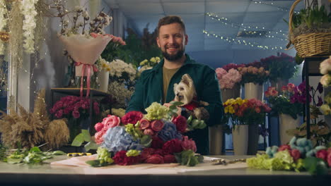 Florist-Keeps-Dog-in-Hands-and-Looks-at-Camera
