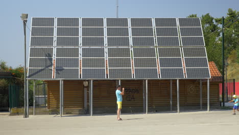 Father-take-picture-of-running-son-along-house-with-solar-panels-on-rooftop-Piraeus-Greece