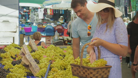 Couple-choosing-grapes-and-speaking-with-smile-on-outdoor-market-Thessaloniki-Greece