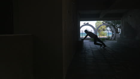 Man-doing-push-ups-in-archway-against-sea-view