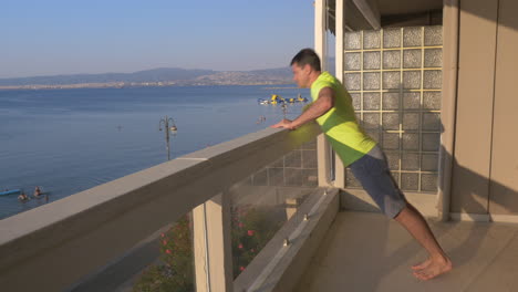 Man-beginning-push-ups-on-the-balcony-with-sea-view-background