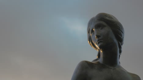 Face-of-Little-Mermaid-statue-against-sky-background