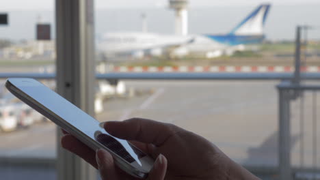 Frau-Schreibt-Am-Flughafen-Eine-SMS-Auf-Dem-Handy