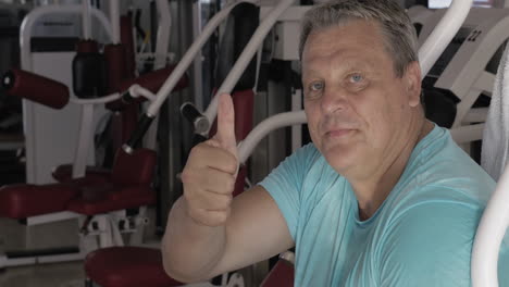 Senior-man-with-thumb-up-and-smile-between-exercises-in-gym