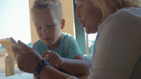 In-city-of-Perea-Greece-sits-a-grandmother-with-her-grandson-and-teaches-him-how-use-tablet