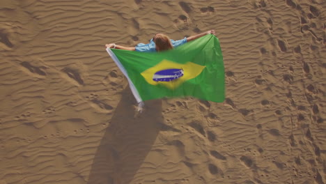Mujer-Con-Bandera-Brasileña-Ondeando-En-La-Vista-Aérea-Del-Viento.