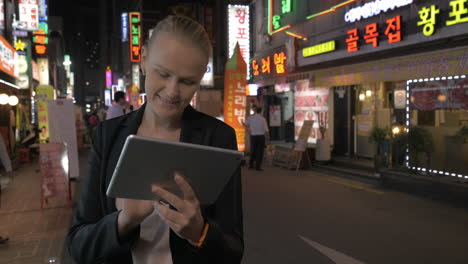 Frau-Mit-Touchpad-Auf-Der-Straße-Von-Seoul-Bei-Nacht,-Südkorea