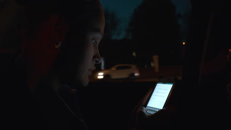 Woman-with-smart-phone-in-car-at-night