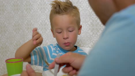 Father-teaching-son-to-use-a-spoon-during-eating