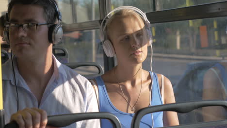Mujer-Y-Hombre-Escuchando-Música-Con-Auriculares-Durante-El-Viaje-En-Autobús.