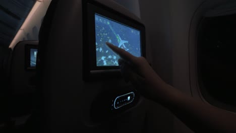 Woman-looking-at-flight-path-on-touchscreen-seat-monitor