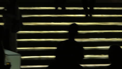 Silhouetten-Von-Menschen,-Die-Vor-Der-Beleuchtung-Einer-Goldenen-Treppe-In-Bangkok,-Thailand,-Auf-Und-Ab-Gehen