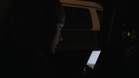 Mujer-Joven-Usando-Teléfono-Celular-Durante-El-Viaje-Nocturno-En-Auto-Por-La-Ciudad