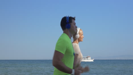 Shot-of-young-woman-and-man-in-headset-are-jogging-on-sea-skyline-background-Piraeus-Greece