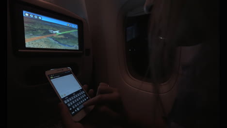 Woman-typing-SMS-during-night-flight