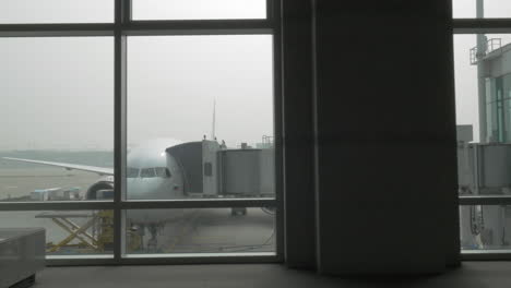 Unloading-the-plane-with-attached-air-bridge-view-from-the-window