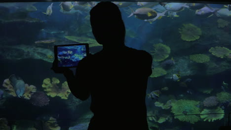 Young-woman-in-Bangkok-Thailand-at-the-oceanarium-of-Siam-Ocean-World-take-pictures-on-her-tablet