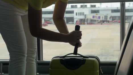 Woman-weighing-luggage-with-hand-scales